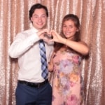 A couple making a heart shape with their hands inside a photo booth