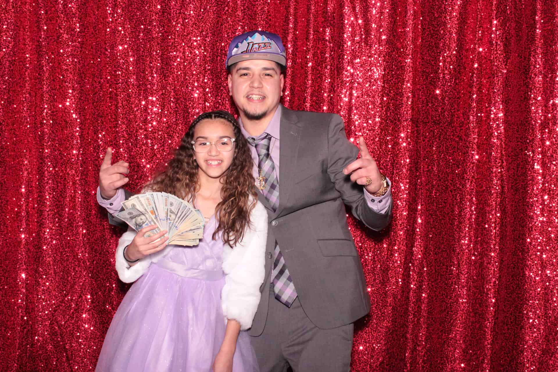 using prop money, two people flashing benjamins inside a photobooth