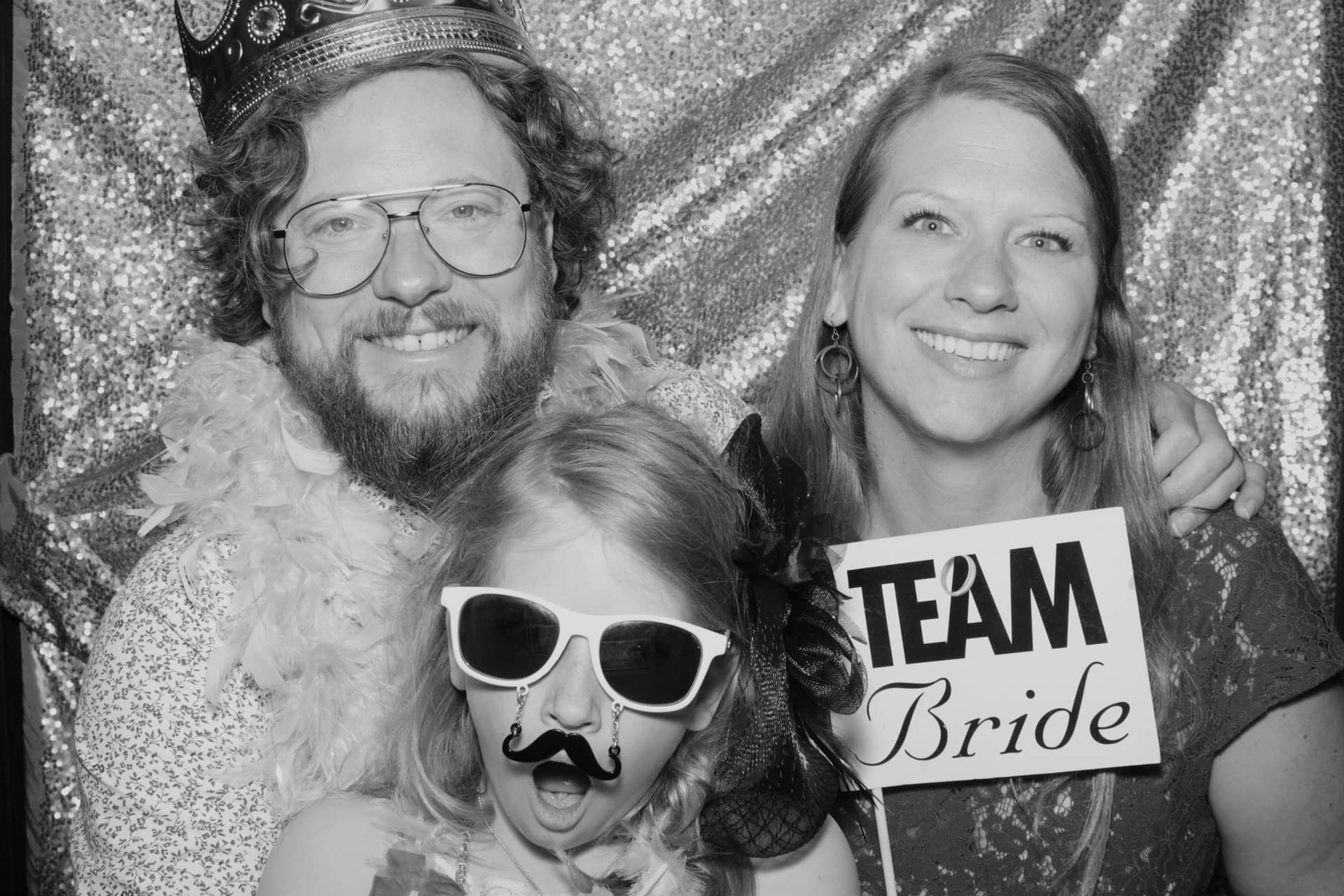 Family taking a black & white photo inside a photo booth with props